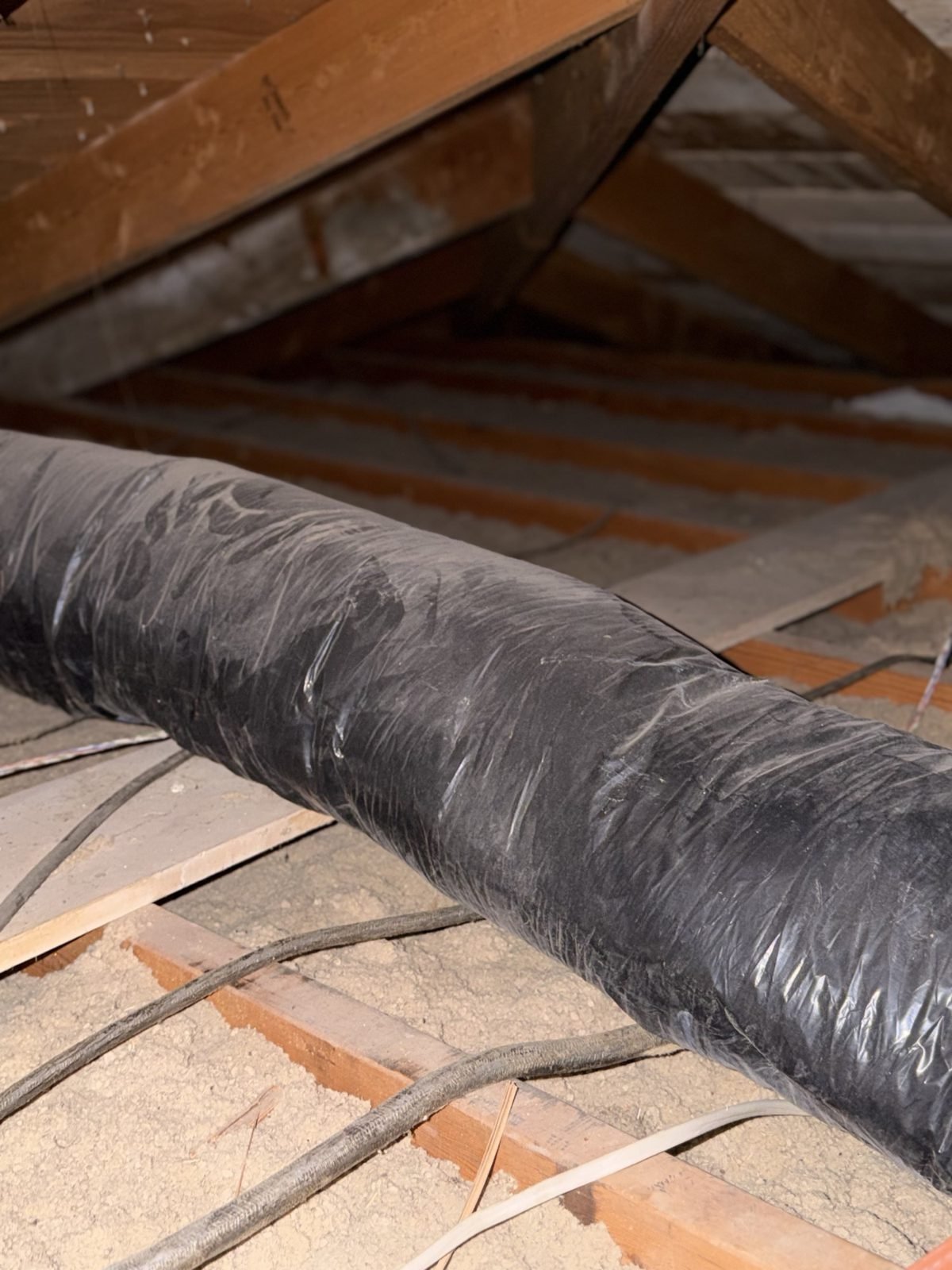 Under-insulated attic before AtticPro service &ndash; exposed ductwork on bare, dusty joists