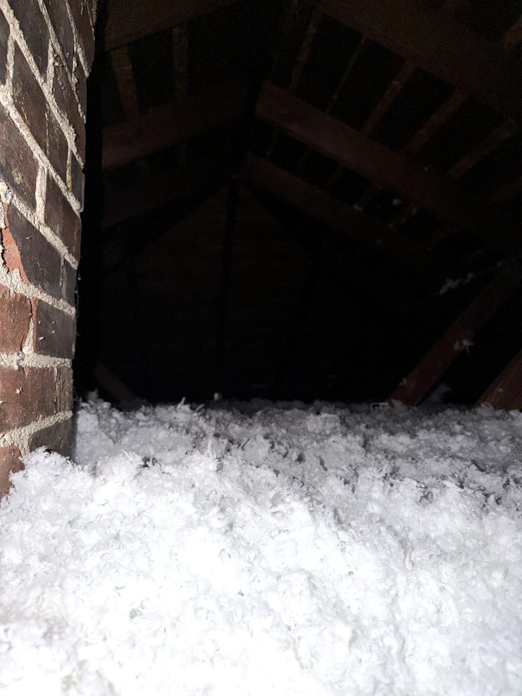 Freshly insulated attic with deep blown-in coverage beside the chimney