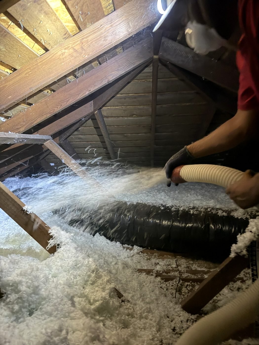 AtticPro crew member blowing fresh blown-in insulation into a Denver-area attic